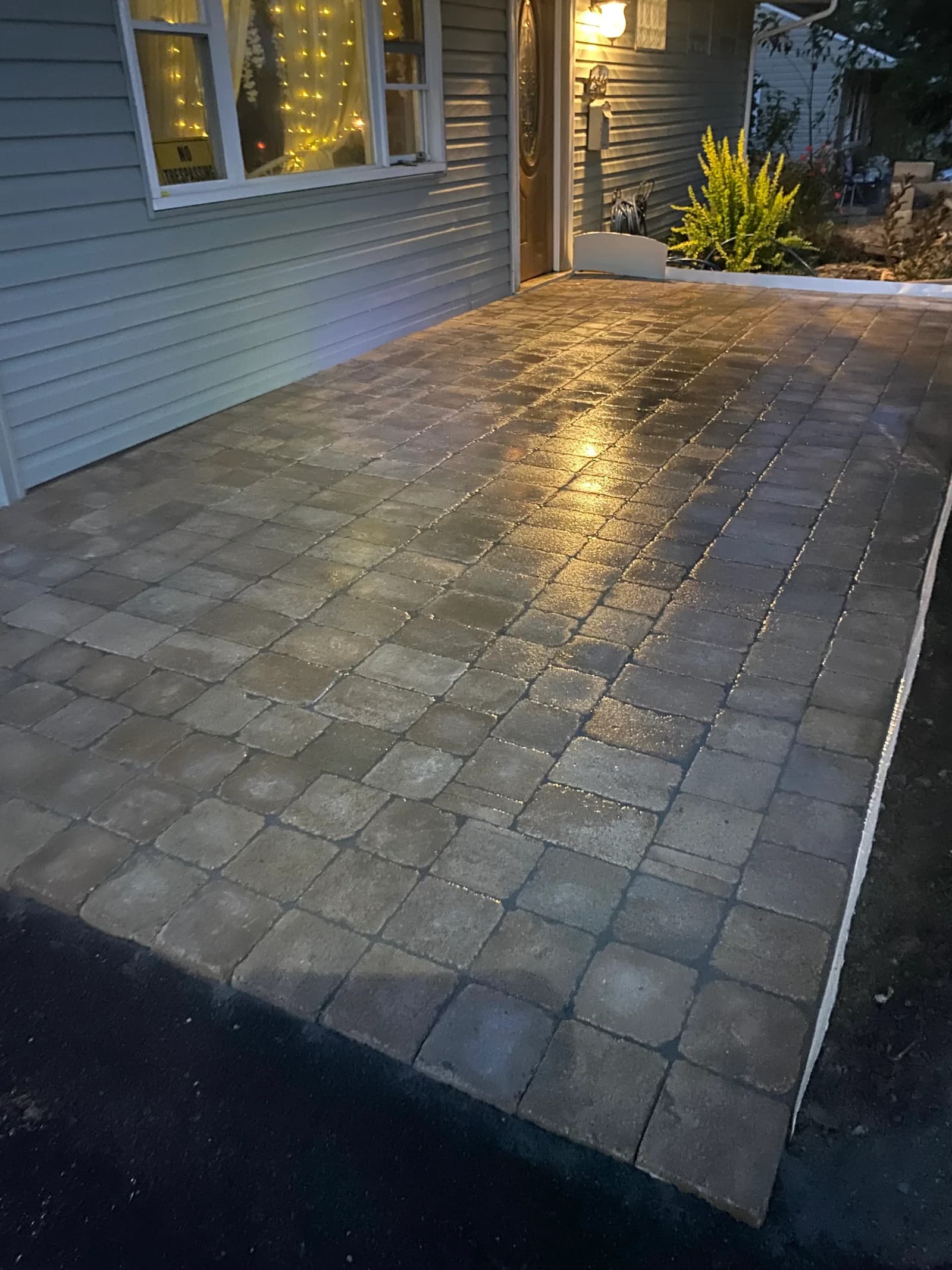 Completed paver patio beside the house, photographed in the evening